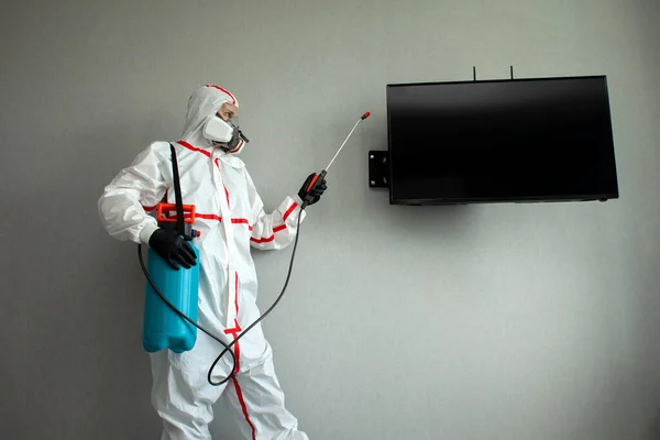 pest control. a man in a chemical suit disinfects the room from rodents and insects, a sanitary worker with a spray on the background of the apartment