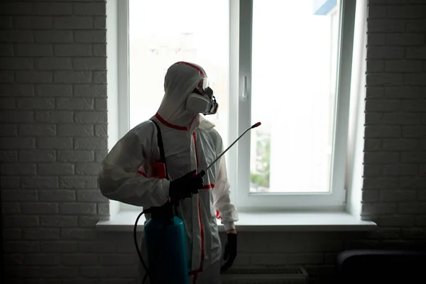 害虫駆除だ 化学スーツの男が部屋を腐敗物や虫から消毒しアパートの裏側にスプレーで衛生的な労働者 — ストック写真