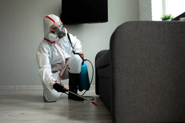 Haşere kontrolü. Böceklere ve kemirgenlere karşı kimyasal yollarla dezenfekte edilmiş bir bina. Evin arka planında spreyi olan bir hijyenik işçi.