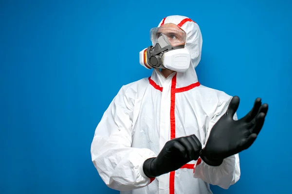 Epidemiologist Chemical Protective Suit Puts Gloves Blue Isolated Background Man — Stock Photo, Image