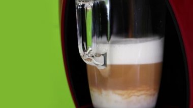 Şeffaf cam bardakta ev yapımı kapuçino karıştırma işlemi