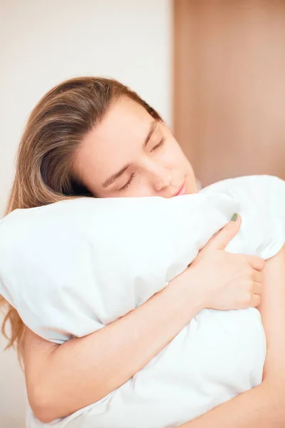 Mulher na cama abraça um travesseiro, foto — Fotografia de Stock