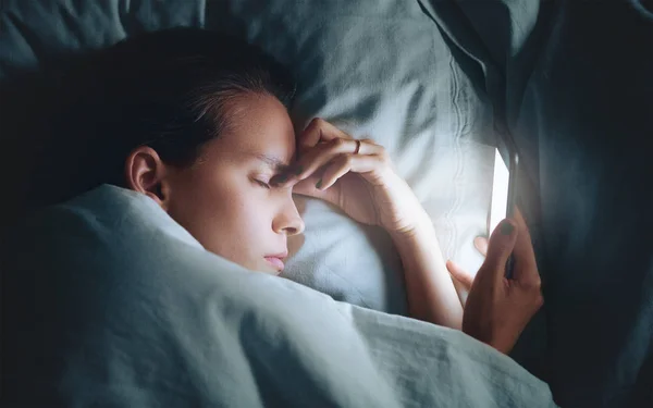 Frau im Bett mit Telefon, Kopfschmerzen — Stockfoto