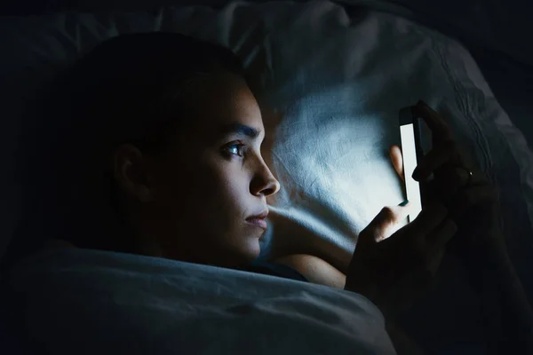 Gece geç saatlerde cep telefonu kullanan genç ve güzel bir kadın. İnternet bağımlılığı konsepti.