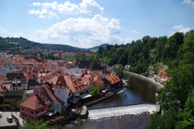 Cesky Krumlov, Güney Bohemya / Çek Cumhuriyeti 07 16 2018: Vltava nehir kıvrımı ve çevresindeki yeşil ormanlık alan ile kentin panoraması. Bir sürü kırmızı çatı ve akıntı görünür.. 