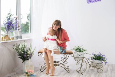 Bir güzel ve genç anne kızıyla birlikte - evde küçük bir bebek kız oynar. Mutlu bir aile fotoğrafı.