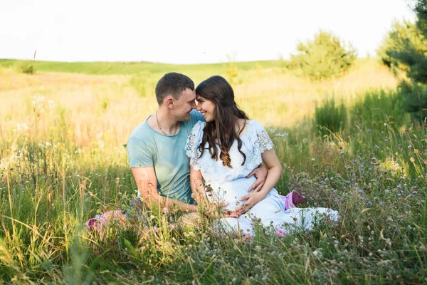 Bir buğday alanında romantik hamile çift portre. Hamile kadın kocasıyla doğada rahatlatıcı güzel güneşli bir günde ayakta