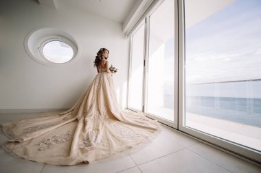 Gelin panoramik deniz manzarası ile beyaz odada uzun tren ile.