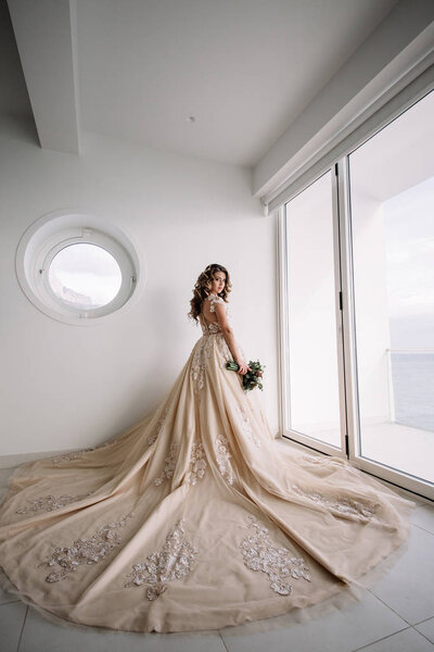 невеста с длинным поездом в белой комнате с панорамным видом на море
.