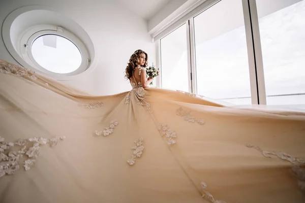 Невеста с длинным поездом в белой комнате с панорамным видом на море . — стоковое фото