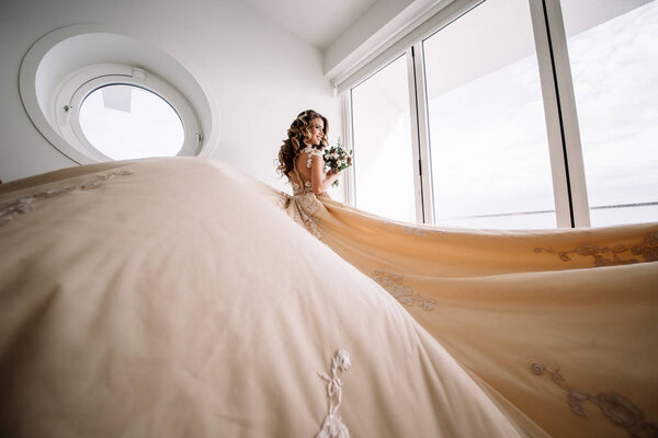 невеста с длинным поездом в белой комнате с панорамным видом на море
.