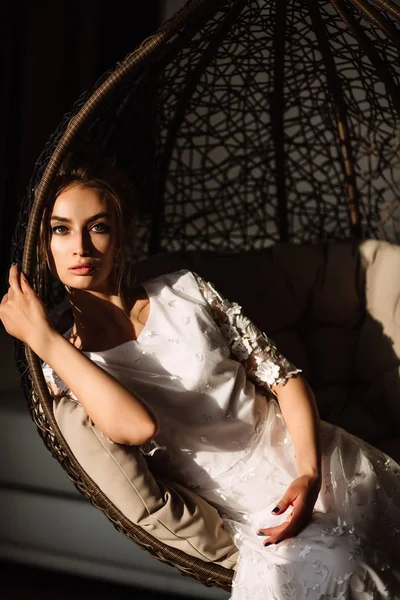 Woman, the bride sits on a wicker swing. Sunny summer day — Stock Photo, Image