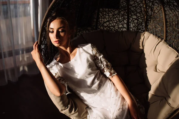 Woman, the bride sits on a wicker swing. Sunny summer day — Stock Photo, Image