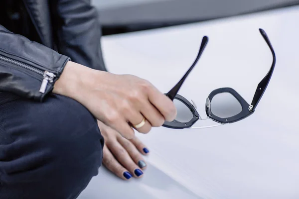 Cerca de los detalles de moda, mujer de negocios joven sosteniendo y gafas de sol, joyas de oro . — Foto de Stock