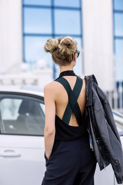 Foto al aire libre de moda de mujer hermosa sexy con pelo oscuro en chaqueta de cuero negro y gafas de sol posando en auto de lujo — Foto de Stock