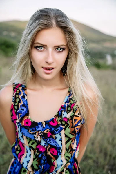 Hermosa rubia con hermosos ojos en mono azul en la naturaleza, sol puesta del sol — Foto de Stock