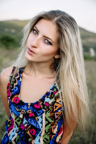 Smuk blondine med smukke øjne i blå overalls i naturen, solnedgang sol - Stock-foto