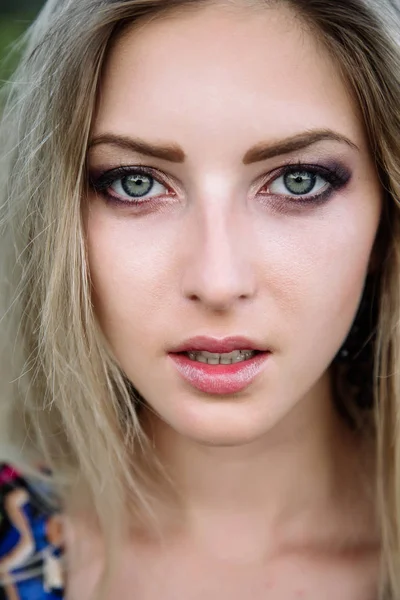 Retrato de una hermosa rubia con hermosos ojos en mono azul en la naturaleza, el sol poniente — Foto de Stock