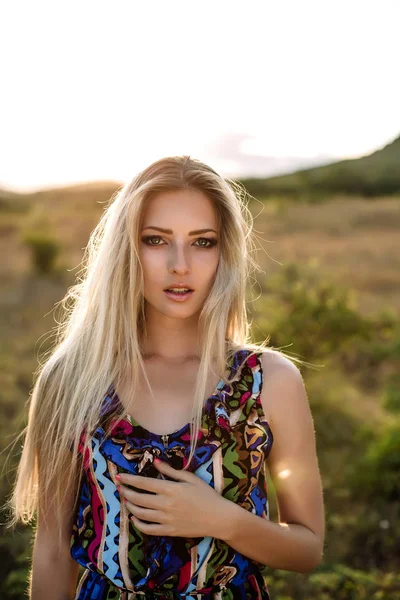 Vacker blondin med vackra ögon i blå overaller i naturen, sunset solen — Stockfoto