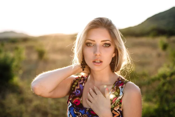 Блондинка с красивыми глазами в синих комбинезонах на природе, заходящее солнце — стоковое фото