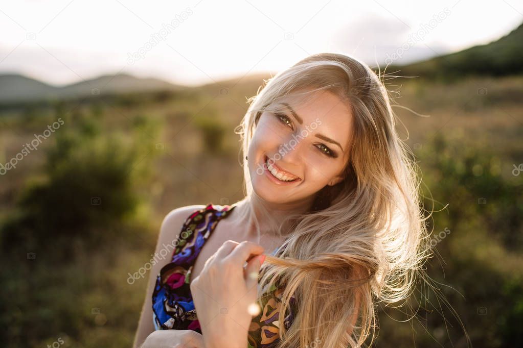 Beautiful blonde with beautiful eyes in blue overalls in nature, sunset sun