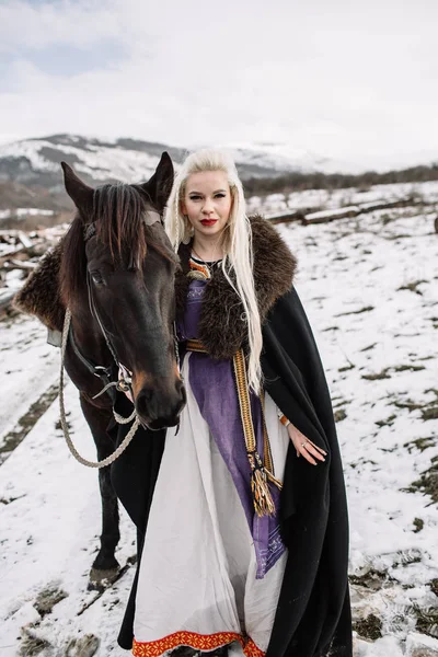 Όμορφη ξανθιά Viking σε μαύρη κάπα έφιππος — Φωτογραφία Αρχείου