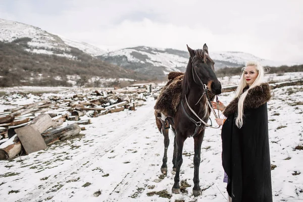 Linda loira Viking em uma capa preta a cavalo — Fotografia de Stock