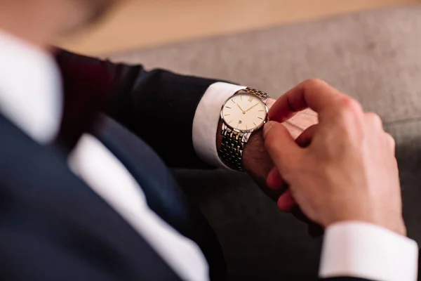 watch with white dial on the hand of a man in a white shirt