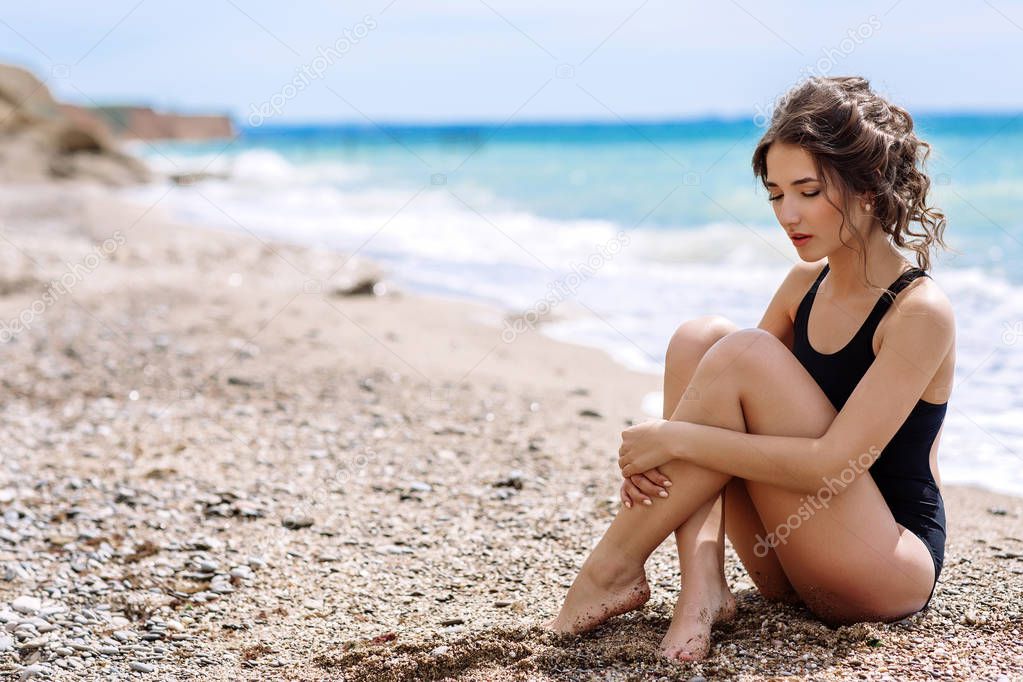 High fashion look.glamor beautiful sexy stylish brunette young female model with bright make-up, with perfect sunbathing clean skin in a black swimsuit on the beach in fashion style