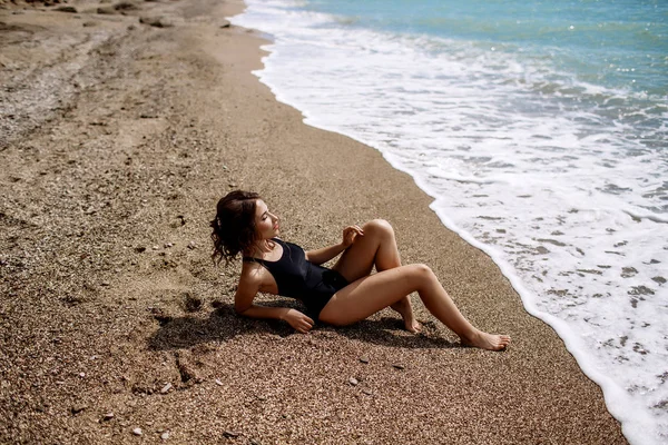 Yüksek moda look.glamor güzel seksi şık esmer genç kadın model mükemmel güneşlenme ile parlak makyajlı bir siyah mayo moda stil sahilde temiz cilt