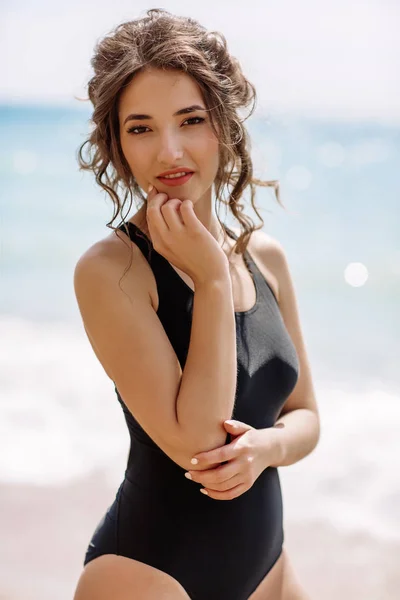 Alta moda look.glamor bela sexy elegante morena jovem modelo feminino com maquiagem brilhante, com perfeito banho de sol pele limpa em um maiô preto na praia em estilo de moda — Fotografia de Stock