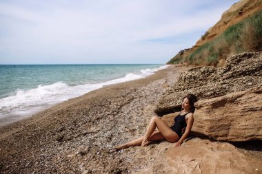 Yüksek moda look.glamor güzel seksi şık esmer genç kadın model mükemmel güneşlenme ile parlak makyajlı bir siyah mayo moda stil sahilde temiz cilt