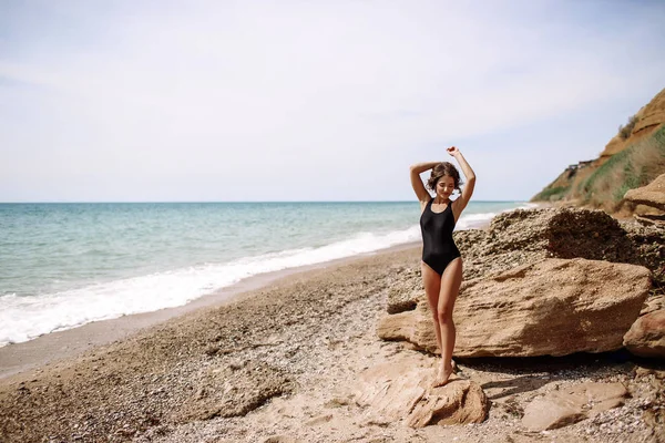 Yüksek moda look.glamor güzel seksi şık esmer genç kadın model mükemmel güneşlenme ile parlak makyajlı bir siyah mayo moda stil sahilde temiz cilt