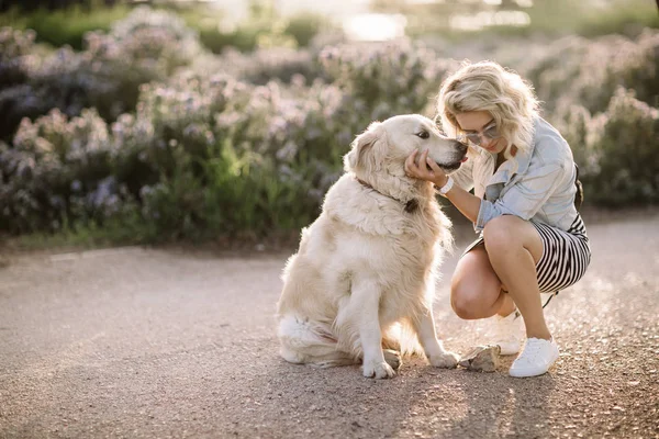 Close-up portrait of rich man playing outdoor with her dog on the street,dog licks his master,girl hugging her puppy,golden labrador puppy,funny mood,positive emotions,kissing lips,walking alone,urban — Stock Photo, Image