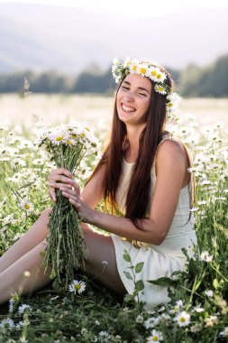 Güzel bir kadın papatya tarlasından zevk alıyor, güzel bir kadın çiçek bahçesinde uzanıyor, güzel bir kız dışarıda dinleniyor, eğleniyor, çiçek tutuyor, mutlu genç bayan ve bahar yeşili doğa, uyum kavramı.