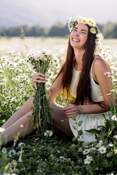 Hermosa mujer disfrutando del campo de margaritas, agradable hembra acostada en el prado de flores, chica bonita relajándose al aire libre, divirtiéndose, sosteniendo la planta, feliz joven dama y naturaleza verde primavera, concepto de armonía — Foto de Stock