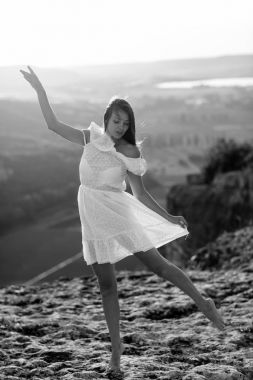 Güzel kız bir dağın tepesinde kalır ve horizon adlı güzel bir arka plan ile görünüyor. Doğal bir günbatımı, inanılmaz bir mucize renkli bir fotoğrafı, bir dans, Rüzgar saçlarında