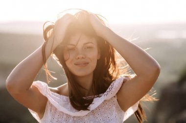 Güzel kız bir dağın tepesinde kalır ve horizon adlı güzel bir arka plan ile görünüyor. Doğal bir günbatımı, inanılmaz bir mucize renkli bir fotoğrafı, bir dans, Rüzgar saçlarında