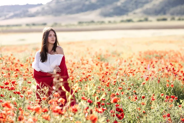 Menina bonita em um campo de papoula ao pôr do sol — Fotografia de Stock