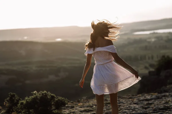 Gyönyörű lány továbbra is egy hegy tetején, és nézi a horizonton, gyönyörű háttér. Egy színes fotót a természetes naplemente, egy csoda, hihetetlen, a tánc, a szél a haj — Stock Fotó