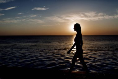 Güzel esmer kız uzun sarı saçlı ve esmer ile iyi durumda bir beyaz mayo mükemmel cilt, havuzun mavi su, yumuşak bir gülümseme ile açık gözler holding ile yalan söylüyor