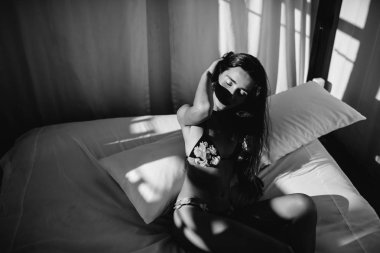 Bikini modeli. Güzel seksi esmer kız modeli uzun dalgalı saçlı, güneş yanığı sahilde moda mayo giyiyor. Tatil. Yanık tenli kadın.