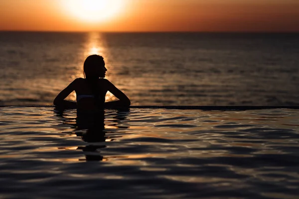 Silueta de una chica en la piscina, rodando en el mar —  Fotos de Stock