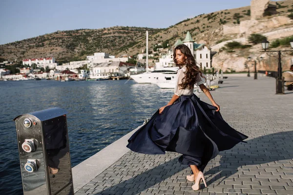 Güzel kız iskelede yürüyüş tarafından denize yakın yat, tekne mavi uzun elbise