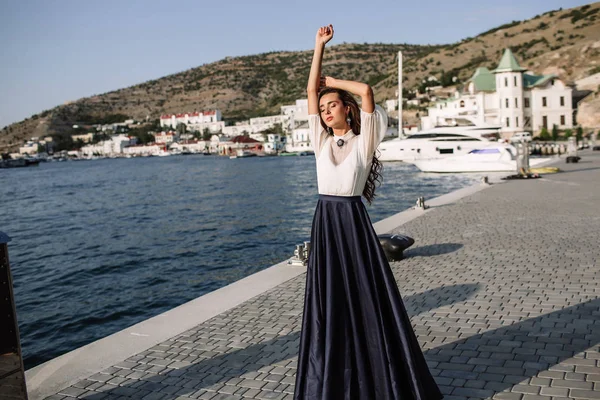 Beautiful girl walking on the pier by the sea near the yacht, boats in the blue long dress — Stock Photo, Image