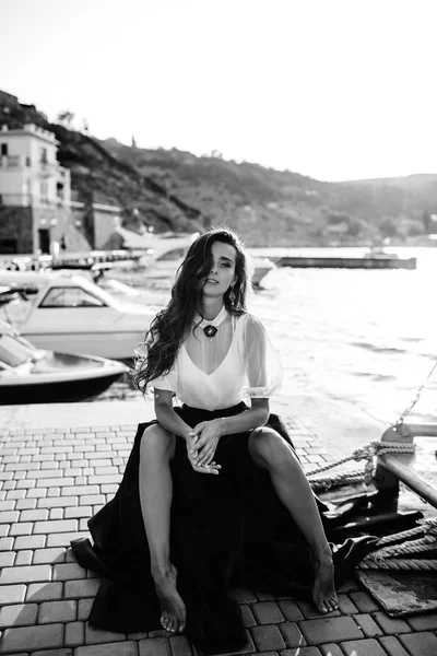 Красивая девушка прогуливается по причалу у моря возле яхты, лодки в синем длинном платье — стоковое фото
