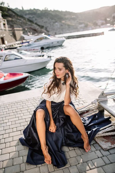 Güzel kız iskelede yürüyüş tarafından denize yakın yat, tekne mavi uzun elbise