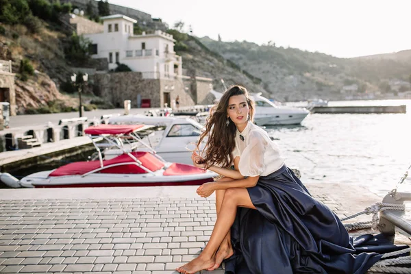 Beautiful girl walking on the pier by the sea near the yacht, boats in the blue long dress — Stock Photo, Image