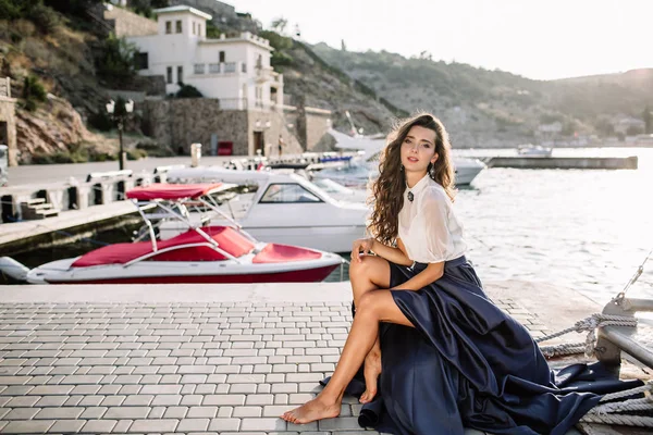 Güzel kız iskelede yürüyüş tarafından denize yakın yat, tekne mavi uzun elbise