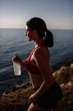 güzel kız ile spor formları spor sahilde, içme suyu, atlama, çalıştırma, farklı egzersizleri yapıyor